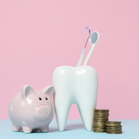 a model tooth next to a piggy bank
