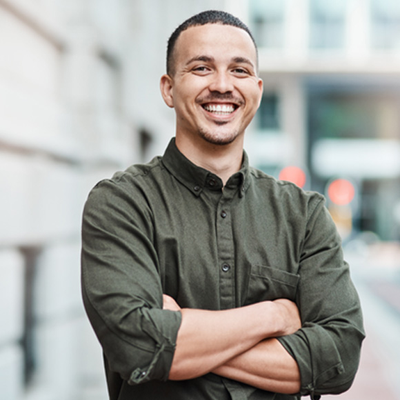 Man in button-up shirt smiling with arms folded