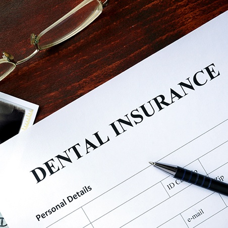 Top of Dental Insurance form with pen, x-rays, and glasses