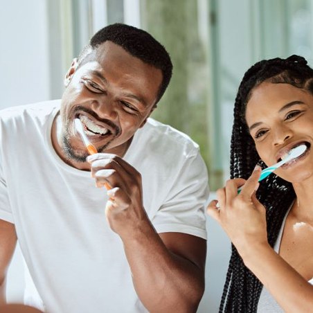 Couple brushing their teeth in front of bathroom mirror