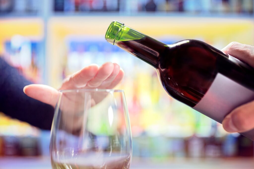 Someone covering their glass so wine can't be poured into it